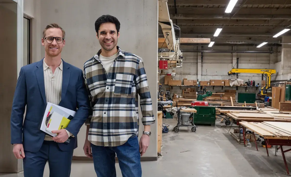 A CWS employee and a client are standing, facing camera, with a production facility on the backgroundd