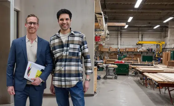 A CWS employee and a client are standing, facing camera, with a production facility on the backgroundd